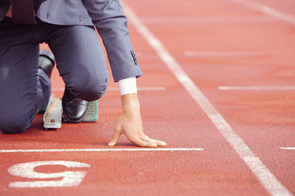 A businessman on a track ready to run fast and efficient